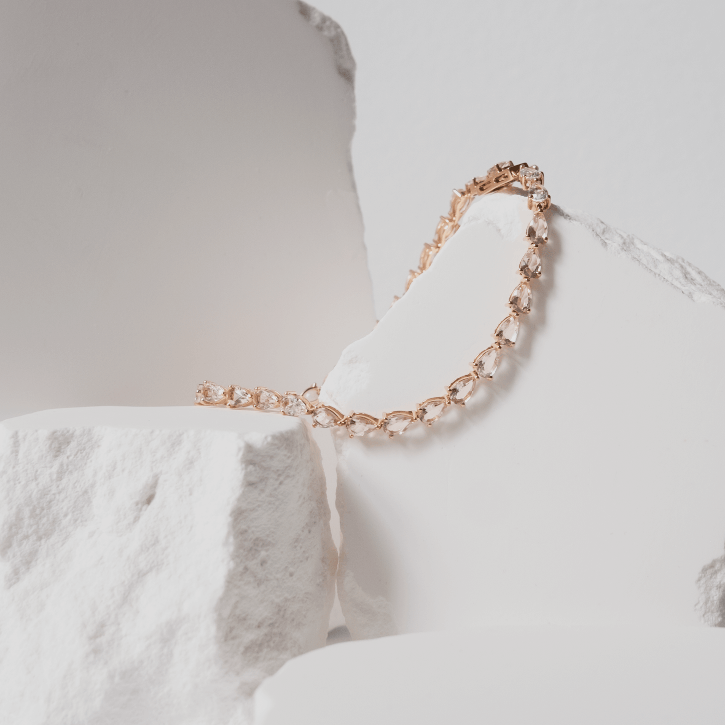 Rose gold bracelet with clear stones on a white marble surface