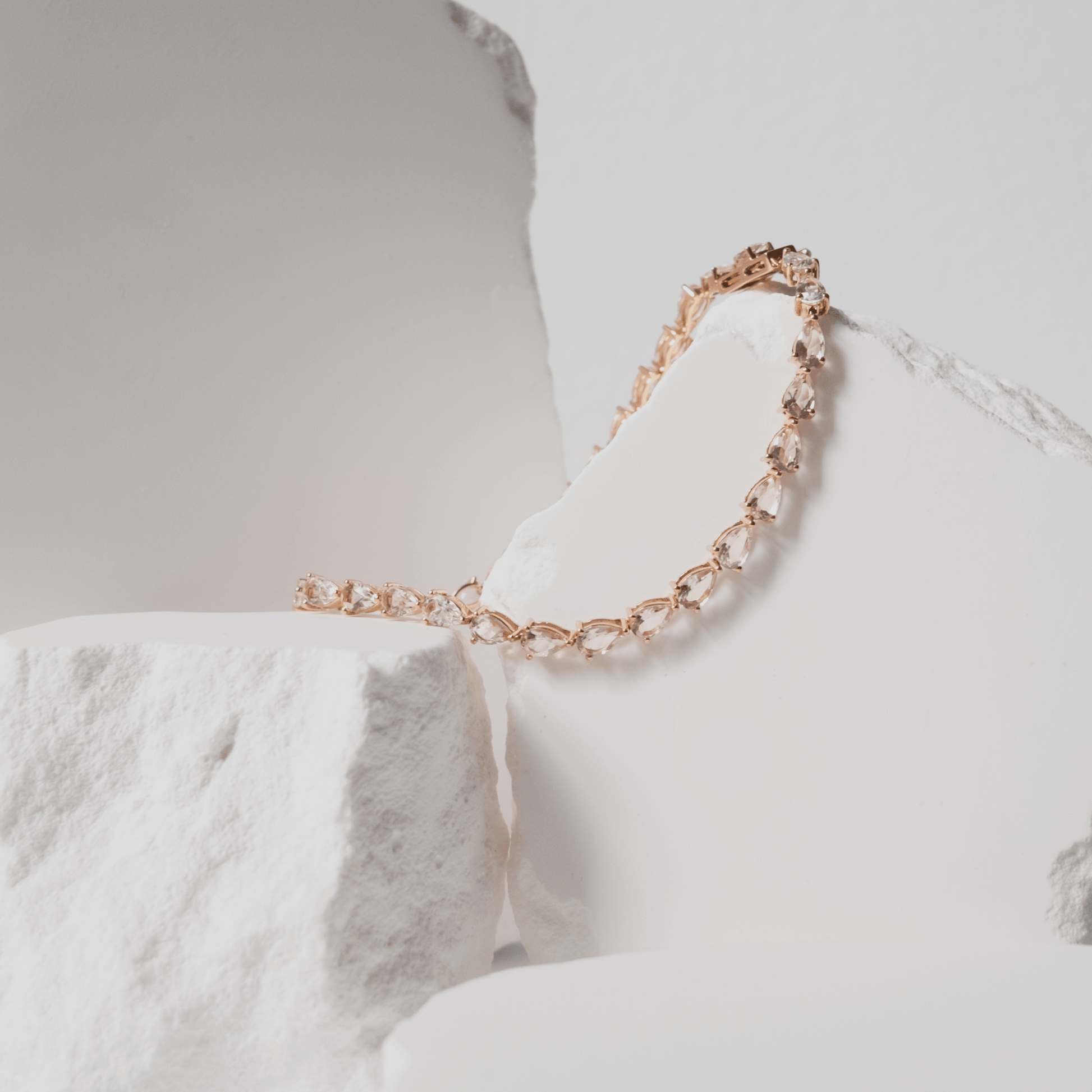 Rose gold bracelet with clear stones on a white marble surface