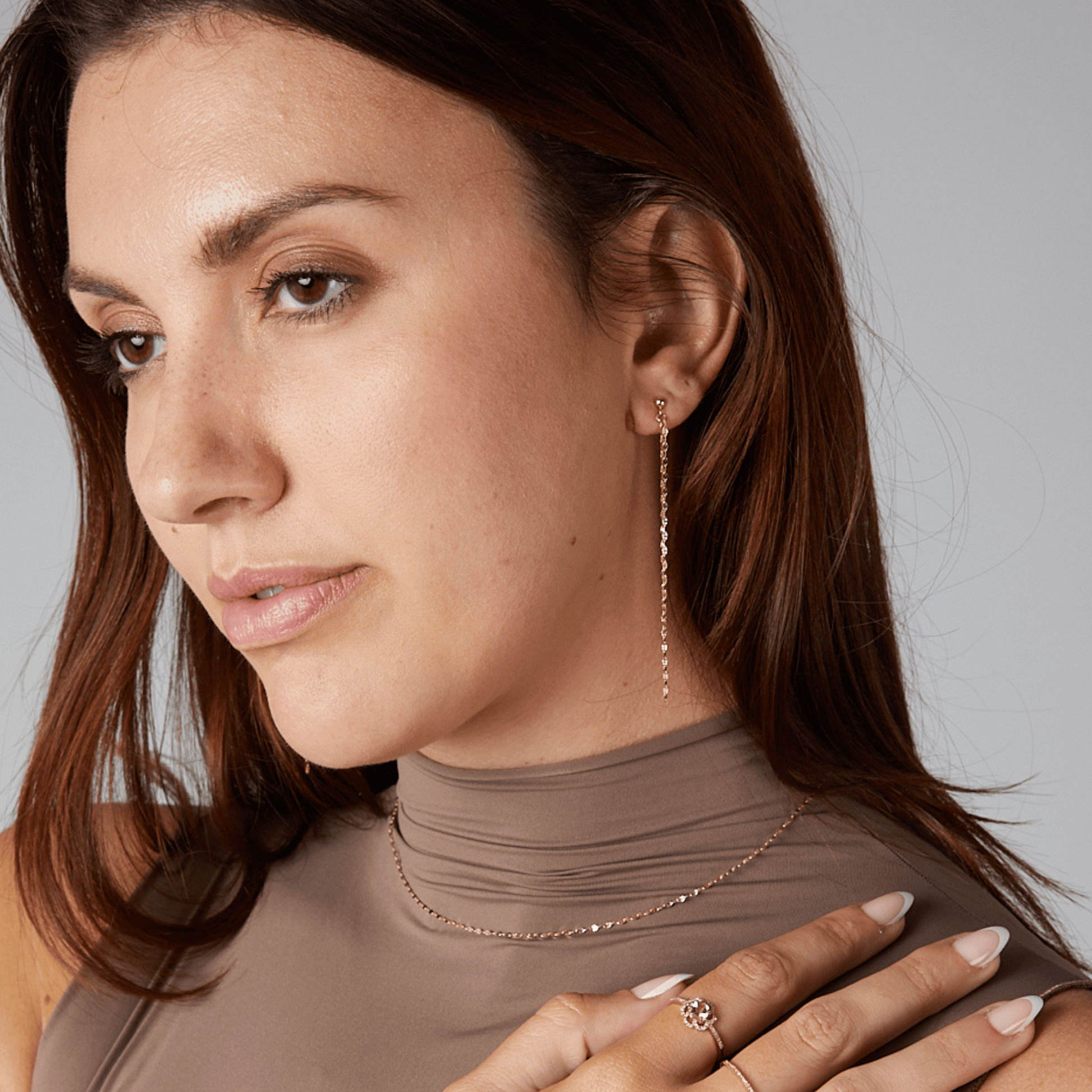 Woman wearing a necklace and earrings with a neutral background