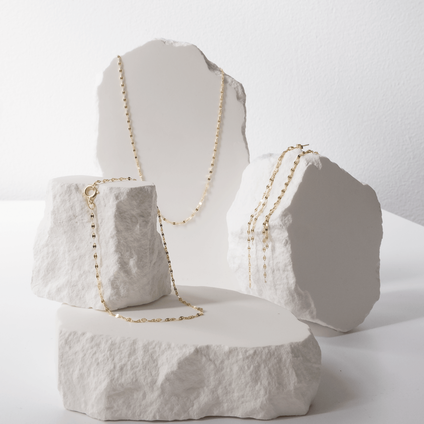 Gold necklace displayed on a textured white surface