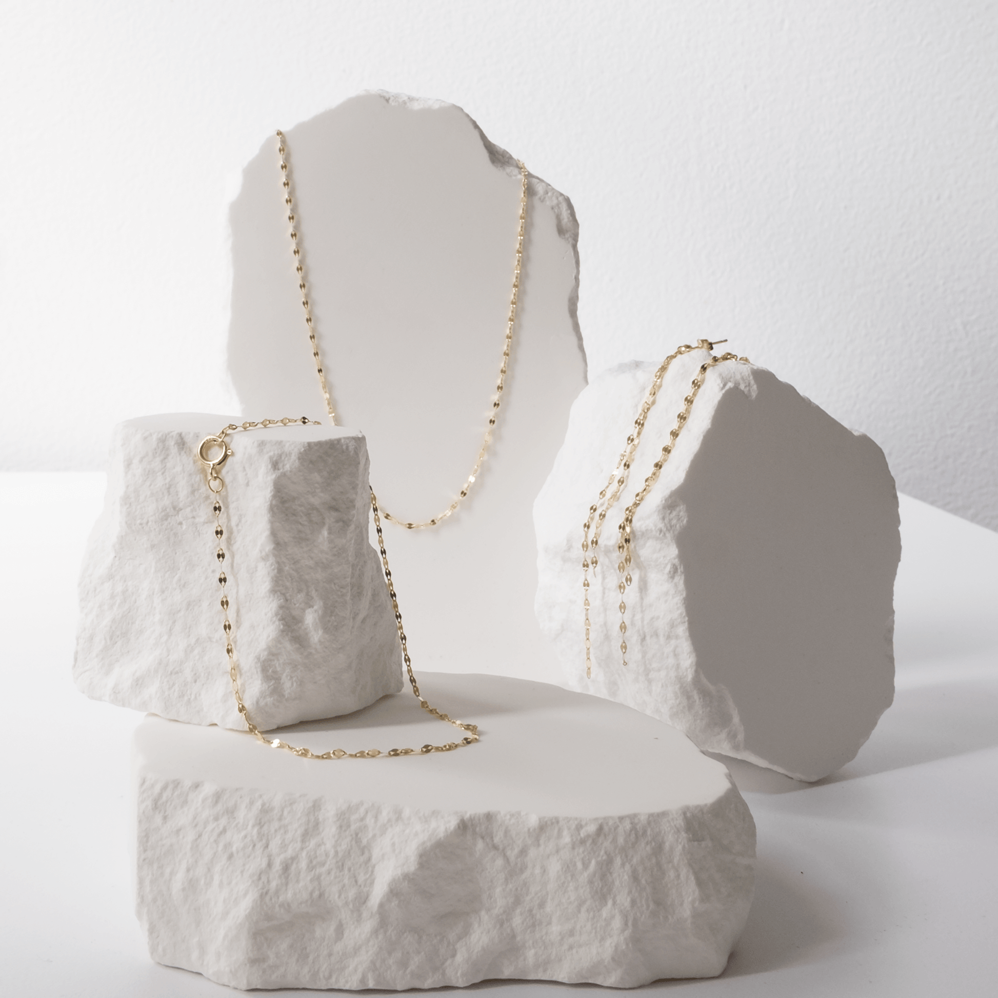 Gold necklace displayed on a textured white surface