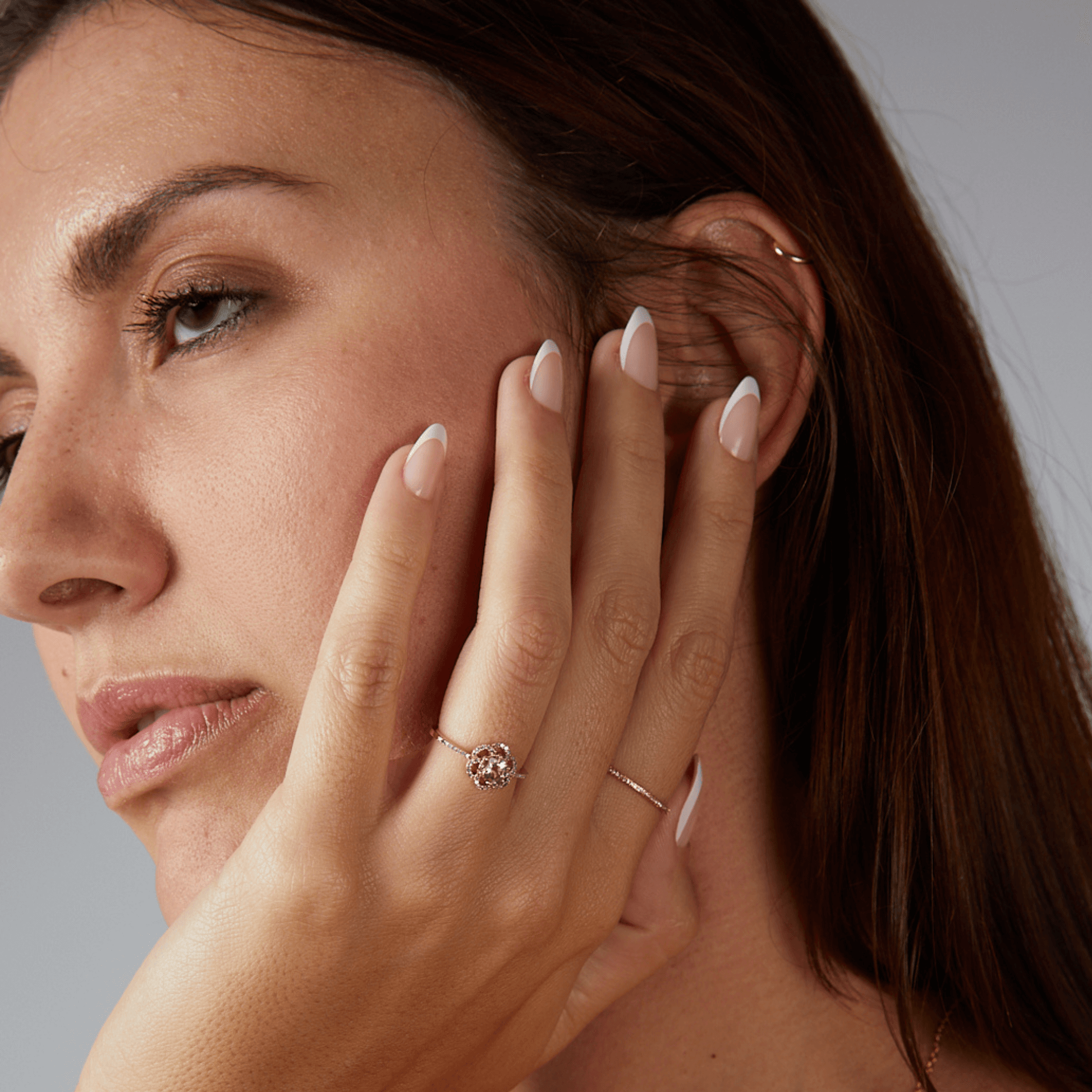 Close-up of a woman wearing a diamond ring on a neutral background