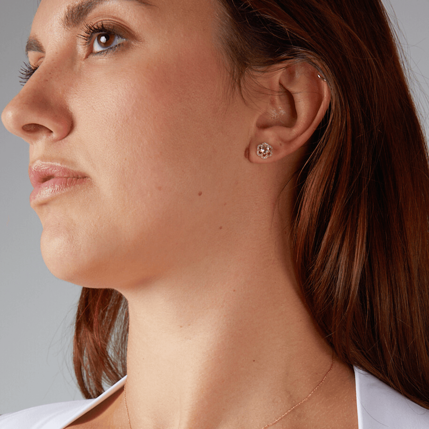 Close-up of a woman wearing a diamond earring against a neutral background