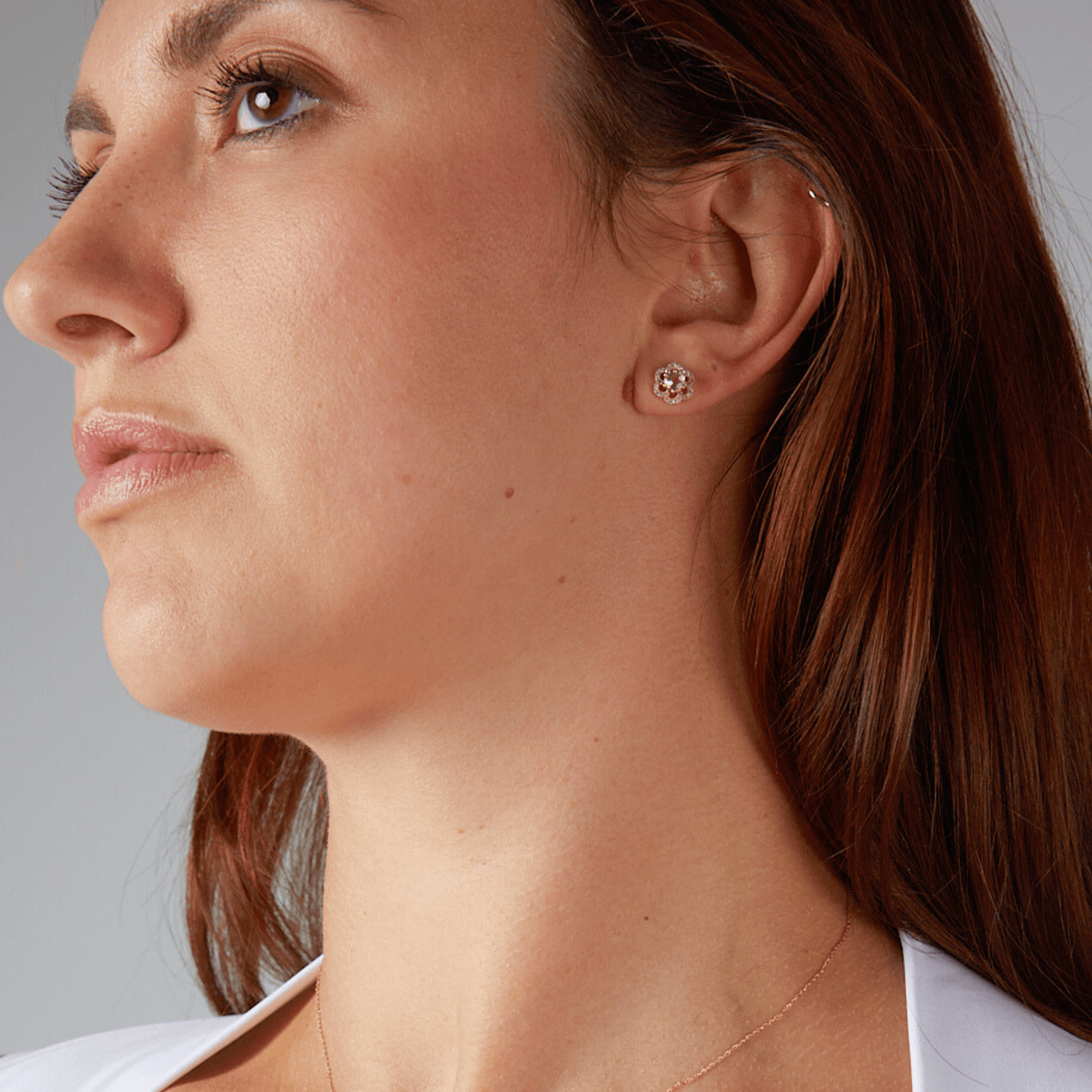 Close-up of a woman wearing a diamond earring against a neutral background