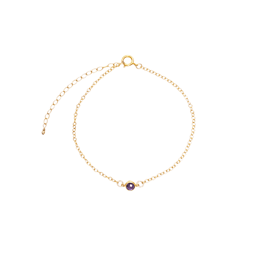 Gold bracelet with a purple gemstone on a white background