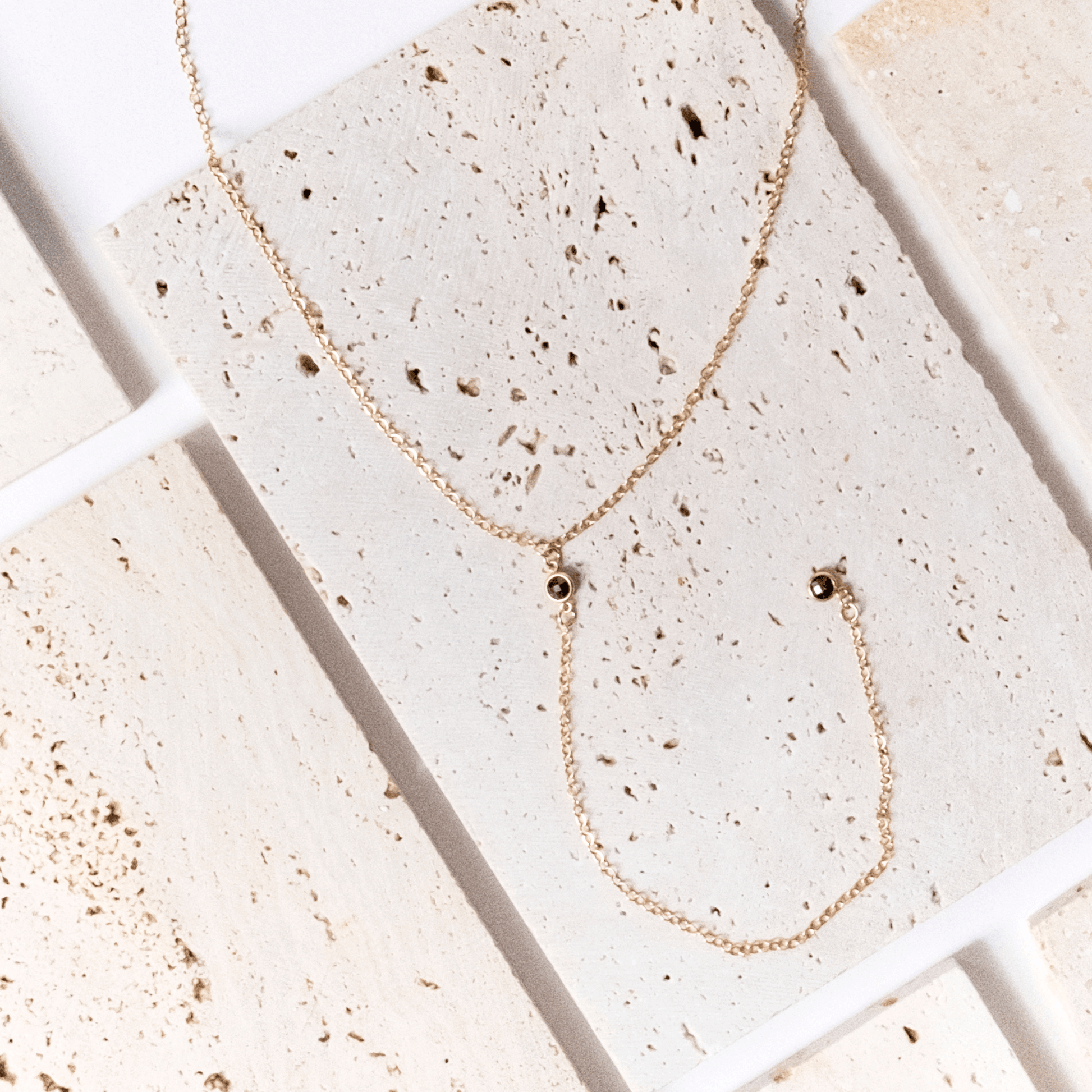 Gold necklace and earring set on a textured stone surface