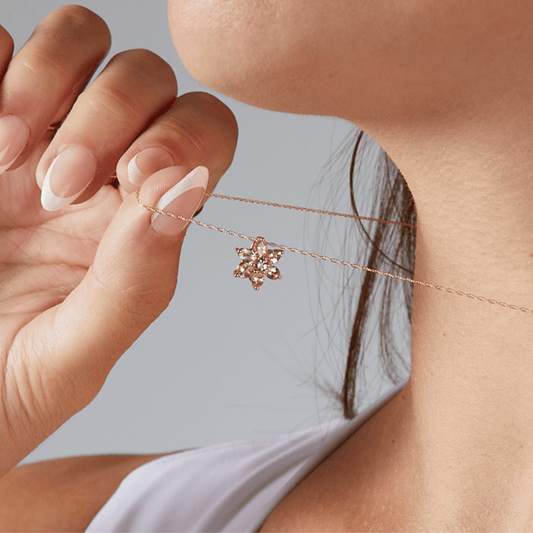 Close-up of a person wearing a delicate necklace with a floral pendant.