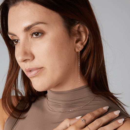Woman wearing a necklace and earrings with a neutral background