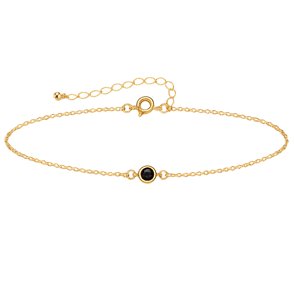 Gold bracelet with a small gemstone on a white background